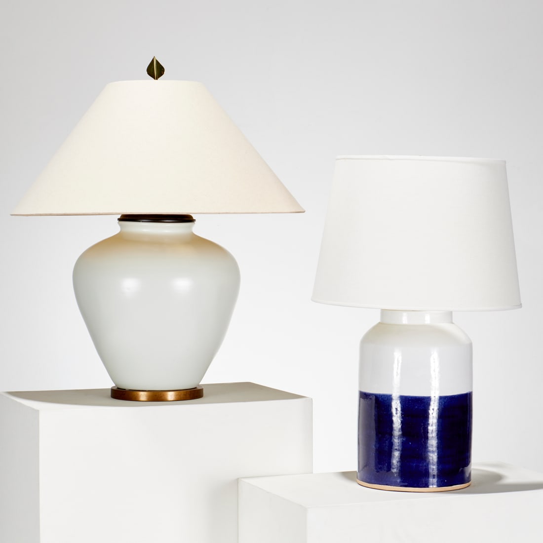 (2) Modern designer ceramic table lamps: (2) Modern designer ceramic table lamps, 21st c., good quality, incl. a navy and white glazed ceramic cylinder lamp, sticker label to underside, 26.5"h x 9.25"dia, (total, excl. shade), with a cream g