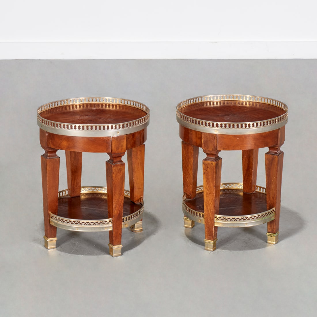 Pair Directoire style mahogany tables: Pair Directoire style mahogany tables, Mid 20th c., of diminutive size, two circular tiers, with pierced brass galleries and sabots, unmarked, 16"h x 13"dia Provenance: The Collection of Charlene