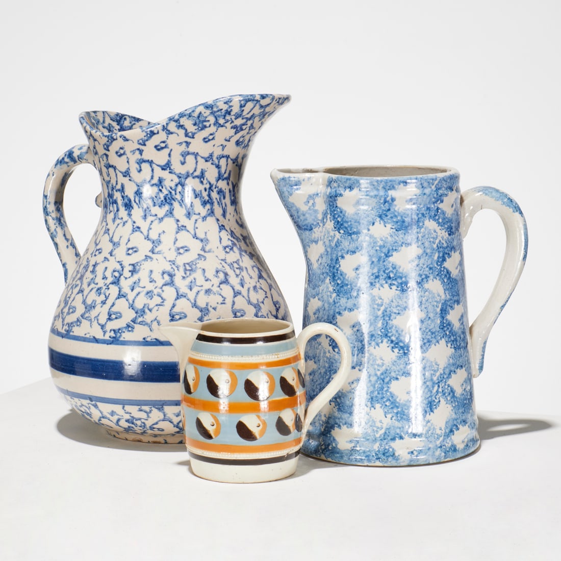 Antique spongeware and mochaware group: Antique spongeware and mochaware group, 19th c., (3) pieces, incl. (2) assorted spongeware pitchers, and a Cat's-Eye decorated mochaware cream jug, 11.5"h x 11"l x 8.5"w (larger pitcher), 9"h x 8"l x