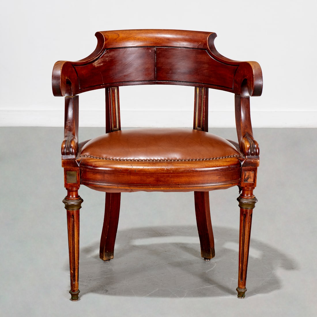 Napoleon III brass mounted fauteuil de bureau: Napoleon III brass mounted fauteuil de bureau, 19th c., France, carved mahogany curved frame, brown leather seat cushion with nail head trim, 31.5"h x 25.5"w x 20"d, 19"h (to seat) Provenance: The Est