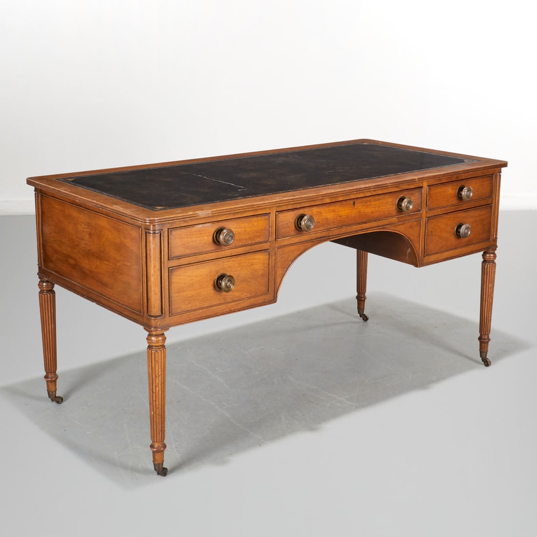 Kittinger Buffalo leather top mahogany desk: Kittinger Buffalo leather top mahogany desk, 20th c., USA, inset embossed leather top, on reeded legs, ending on casters, stamped to drawer interior, 30.5"h x 60"w x 29"d