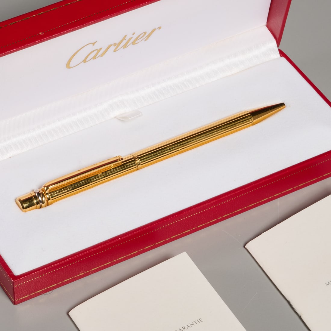 Cartier "Le Stylo Bille" pen with box: Cartier "Le Stylo Bille" pen with box, 20th c., France, no. 018305, gold finish ballpoint pen in original leather box, with two booklets, 5.25"l (pen), 1.25"h x 7"l x 3"d (box) Provenance: The Collect