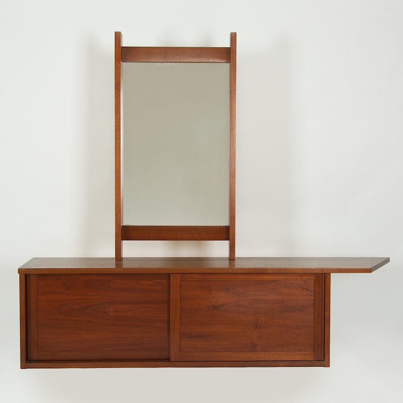 George Nakashima sliding door cabinet and mirror: George Nakashima sliding door cabinet and mirror, Circa 1960/70s., wall hung walnut cabinet with partial dovetailed case, both unmarked, 16"h x 60"l x 12"d (cabinet), 19.5" x 37" (mirror)