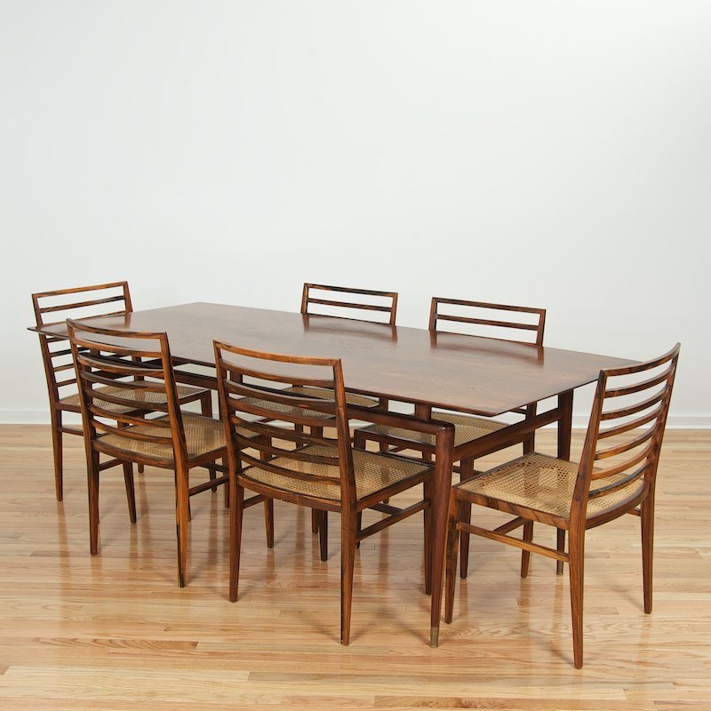 (6) Joaquim Tenreiro dining chairs and Brazilian table: (6) Joaquim Tenreiro dining chairs and Brazilian table, Mid 20th c. 30"h x 87"l x 37"w (table), 34"h x 20"w x 17.5"d (chairs) Provenance: Espasso, NY