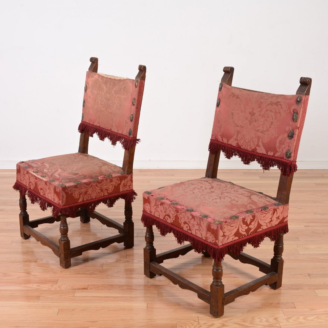 Pair Italian Renaissance carved walnut side chairs: Pair Italian Renaissance carved walnut side chairs, 16th/17th c., possibly Tuscan, reeded forward-scrolling finials, red damask seating, turned legs, 40"h x 20.5"w x 18"d Provenance: Deaccessioned fro