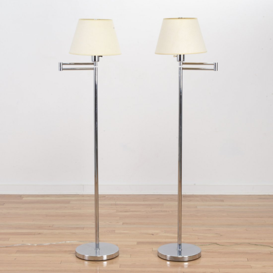 Pair Hansen, NY chrome swing arm floor lamps: Pair Hansen, NY chrome swing arm floor lamps, Circa 1960's, swing arm, round base, base marked "Hansen Lighting Co.", 53"h x 13"dia. (variable)