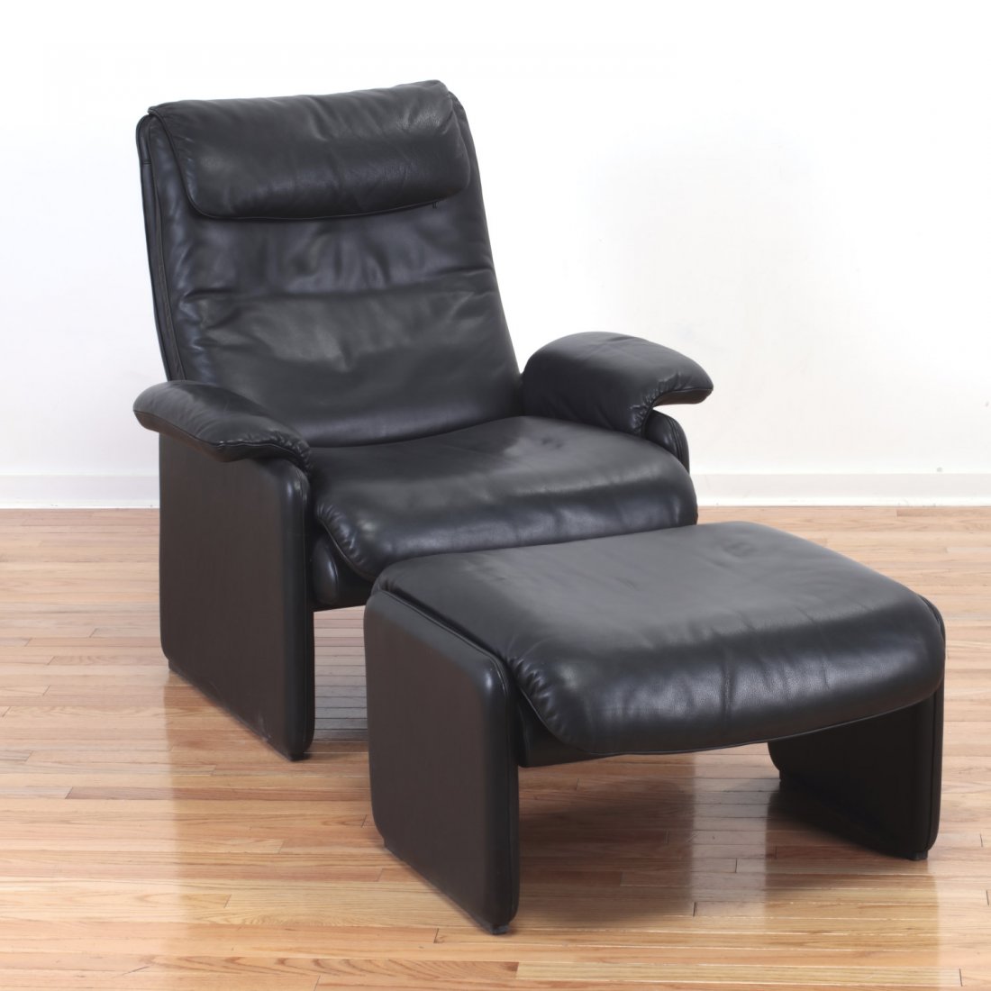 De Sede black leather reclining armchair/ottoman: De Sede black leather reclining armchair/ottoman, 20th c., label "Made in Switzerland", to underside, "de Sede" lining, 37"h x 33"w x 35"d