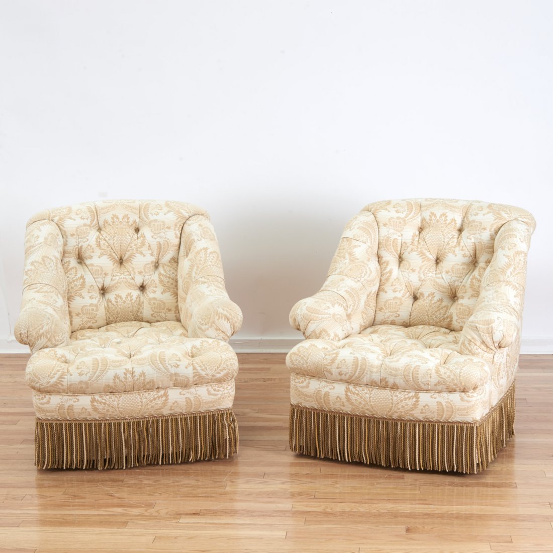 Pair Turkish Revival style swivel bergeres: Pair Turkish Revival style swivel bergeres, 20th c., button tufted gold and ivory upholstery, with fringe skirts, 32"h x 40"w x 34"d