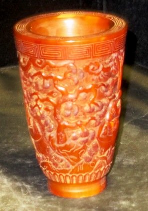 CHINESE CARVED HORN LIBATION CUP: Chinese relief carved horn libation cup that depicts a scene of a child on boat and wiseman with two attendants. Also in the scene are trees, rock formations and pagodas. Measures 3 3/4" height x 2 1/