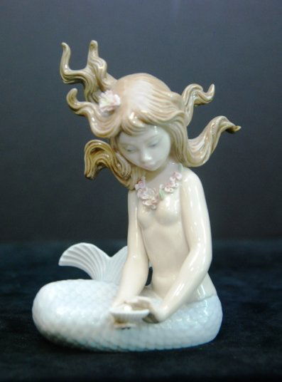 LLADRO PORCELAIN MERMAID "MIRAGE" #1415 Lladro: LLADRO PORCELAIN MERMAID "MIRAGE" #1415 Lladro porcelain figurine of a mermaid with a shell. Title: Mirage. Model #1415 Height: 5.5" Tall by. 4.5" Wide. Weight: 259.60 Grams. Comes on Wood Base.