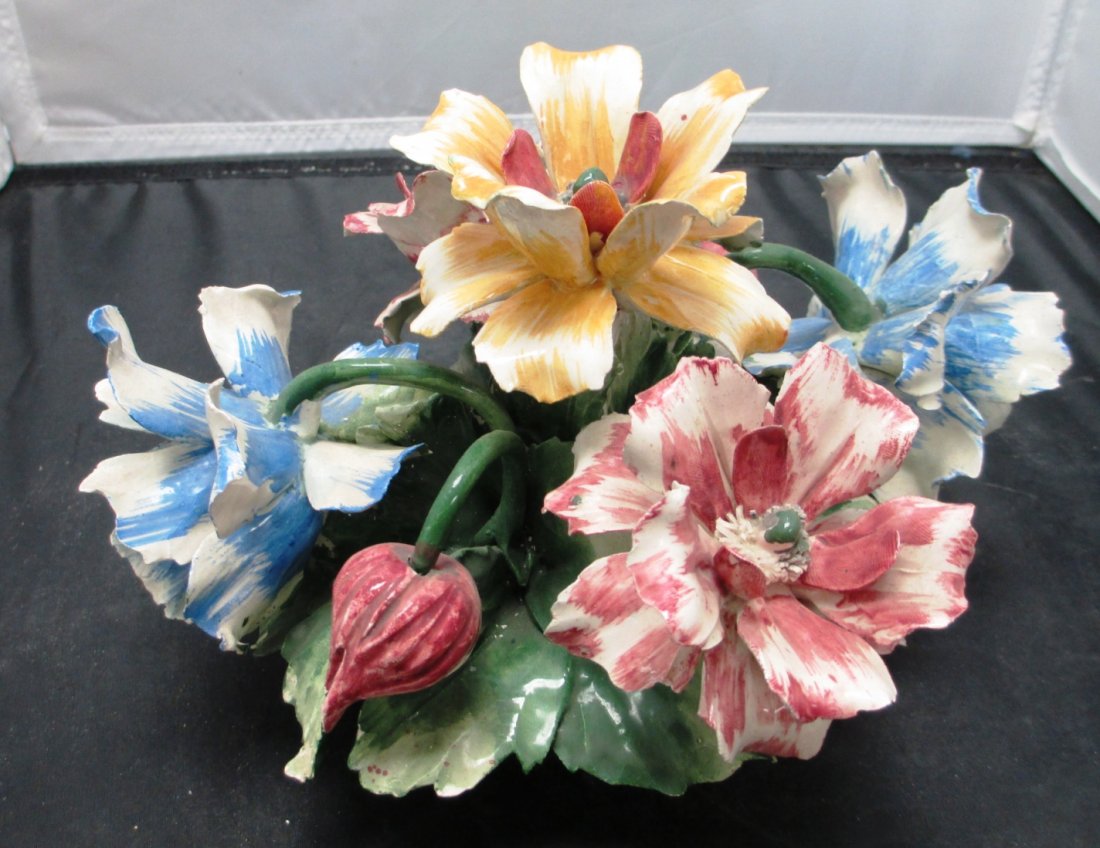 LARGE CAPODIMONTE FLORAL CENTER PIECE: LARGE CAPODIMONTE FLORAL CENTER PIECE 5 Open Flowers of Blue, Pink, and Yellow with 2 Pink Buds under Green Leaves in a Basket measures 7 1/2" Tall by 10" Long.