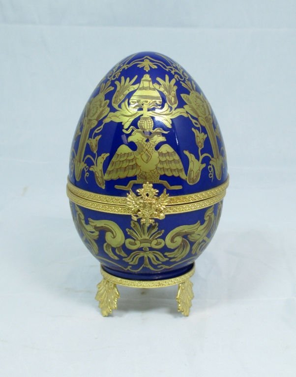 LIMODGE FABERGE IMPERIAL CZAREVICH EGG: A Limoges porcelain egg decorated in Cobalt Blue and 24k gold, opening to a sterling silver and gold vermeil folding picture frame. Marked "Faberge" with hall marks. Signed on underside "Peint Main A.