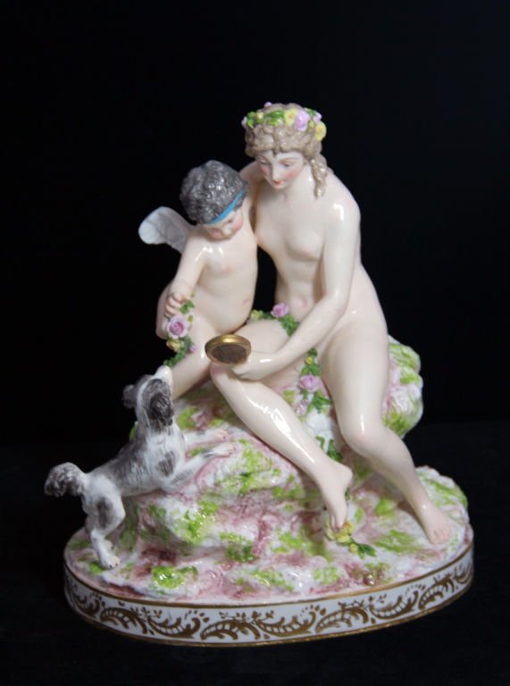 ANTIQUE MEISSEN PORCELAIN FIGURAL GROUP: Statue depicts Nude Woman with Floral Head Dress holding up Mirror with her arms around Cherub. Springer Spaniel Dog is watching them from below. Scene is set on Floral Rock Base measures 10" Tall by