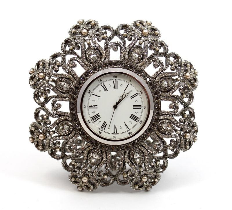 JAY STRONGWATER JEWELED DESK CLOCK: Jay Strongwater jeweled clock having a round star design. Set with white stones and pearls. White enamel face with black Roman Numerals. Black hour, minute and second hand. Quartz movement. Includes b