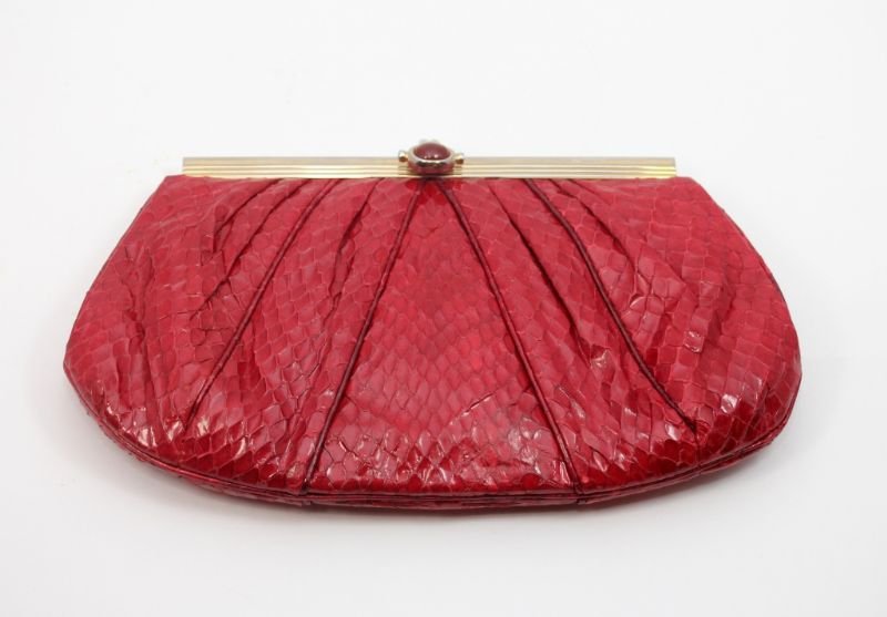 JUDITH LEIBER RED SNAKE SKIN LEATHER CLUTCH PURSE: Judith Leiber designer red snake leather clutch purse. Red silk interior. One zippered pocket to interior. Gold tone hardware with hideaway strap. Measures 5 3/4" height x 9" width.