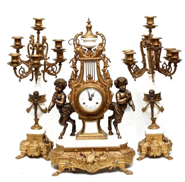 20th CENTURY FRANZ HERMLE CLOCK GARNITURE SET: A Franz Hermle Germam Imperial gilt bronze and white marble clock garniture set having a figural Pan design. Movement having Franz Hermle 130-070 floating balance movement. Set includes two 7 arm cand