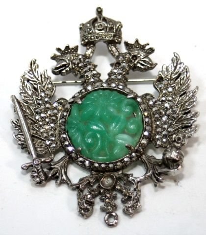 RUSSIAN WHITE METAL MARCASITE JADEITE EAGLE BROOCH: A Russian jeweled white metal double headed eagle brooch featuring a round apple green jadeite plaque to center and numerous marcasite stones. Measures 2 3/8" length x 2" width. Total weight of 19.7 g