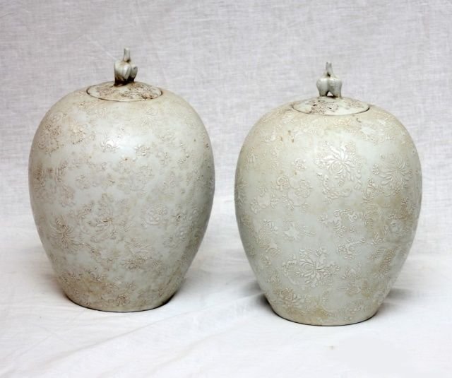 Pr CHINESE QING PORCELAIN WHITE ENEMELED JARS: A pair of antique Chinese white enameled porcelain covered ginger jars. Each with white enameled designs depicting flowers, gourds, peaches, pomegranates and butterflies. Figural peaches finial to cov