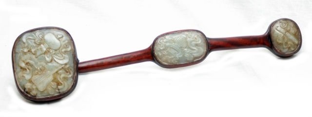 CHINESE HETIAN JADE MOUNTED TEAKWOOD RUYI SCEPTER: 20th century teakwood Ruyi scepter mounted with three high relief carved white He Tian jade plaques. Plaques depict scrolls, planters and hulu gourds. Each plaque having a translucent white to pale gr