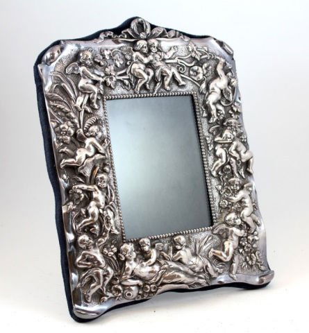 CONTINENTAL STERLING SILVER CHERUBS PICTURE FRAME: Antique Continental sterling silver repousse picture frame depicting a woman to bottom with cherubs and flowers throughout. Marked 'RC 925'. 20th century. Measures approx. 11 1/2" height x 9 1/2" widt