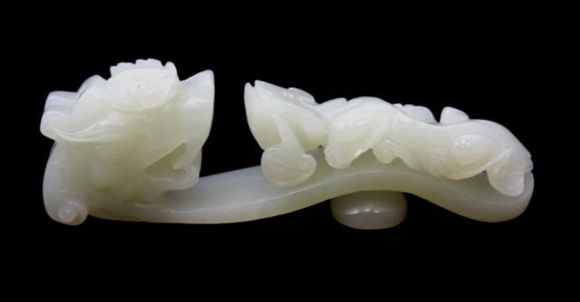 CHINESE WHITE HETIAN JADE RUYI DRAGON GARMENT HOOK: A fine Chinese carved figural ruyi scepter garment hook depicting Chih Lung Dragons holding lingzhi fungus. Attractive even tone white jade with some translucence. Measures 4" length. Total weight of 