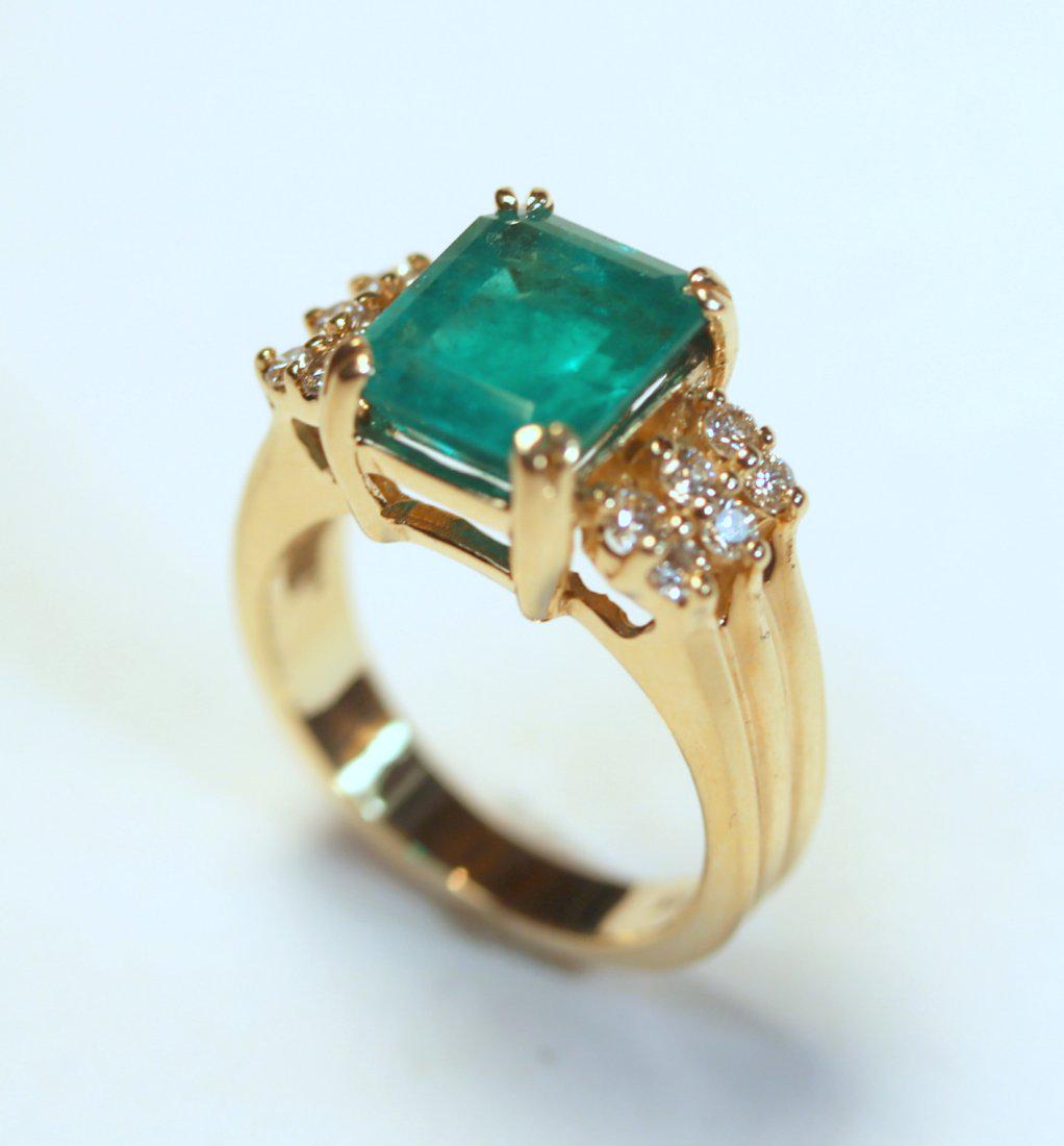 Emerald & Diamond 14K Yellow Gold Ring: Emerald cut emerald set in 14k yellow gold and secured by four split prongs. Ring is accented with twelve round brilliant cut diamonds and a triple ridge design. TW of Colored Stone: 3.65ct TW of Diam