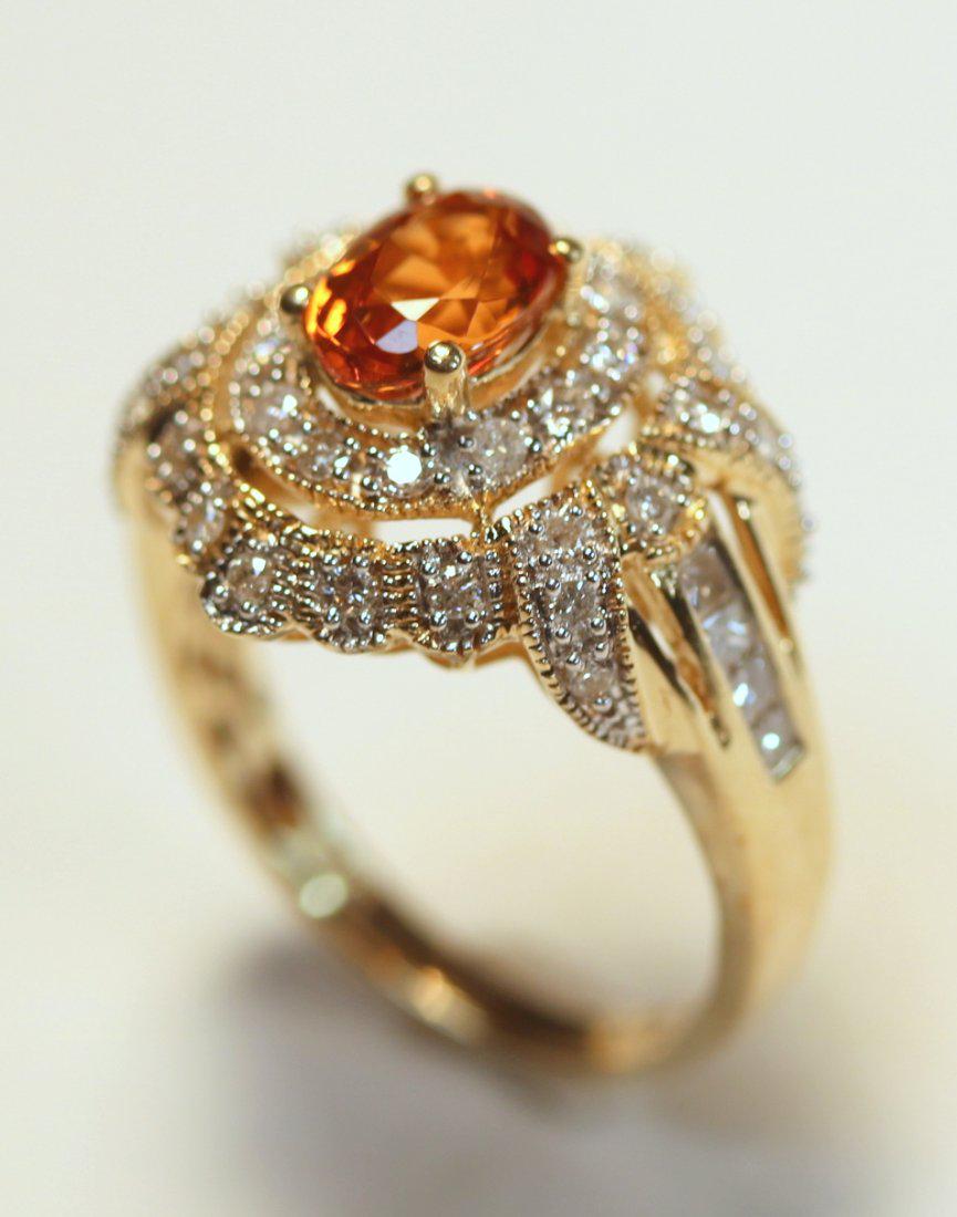 14K yellow Gold Spessartine Garnet & Diamond Ring: 14k yellow gold ring features a spessartine garnet gemstone surrounded by a halo of twelve round brilliant cut diamonds, accented by additional thirty-two diamonds. TW of Colored stone: 1.30ct TW of D