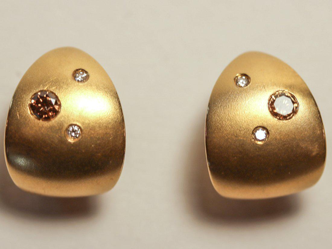 Argyle Champagne Diamond 18K Yellow Gold Earrings: 18k yellow gold, matte finish earring with omega clip backs with posts. Each earring has a flush set Argyle Champagne diamond (o.44ct) and two flush set diamonds (0.08ct). TW of Diamonds: 0.52ct TW of
