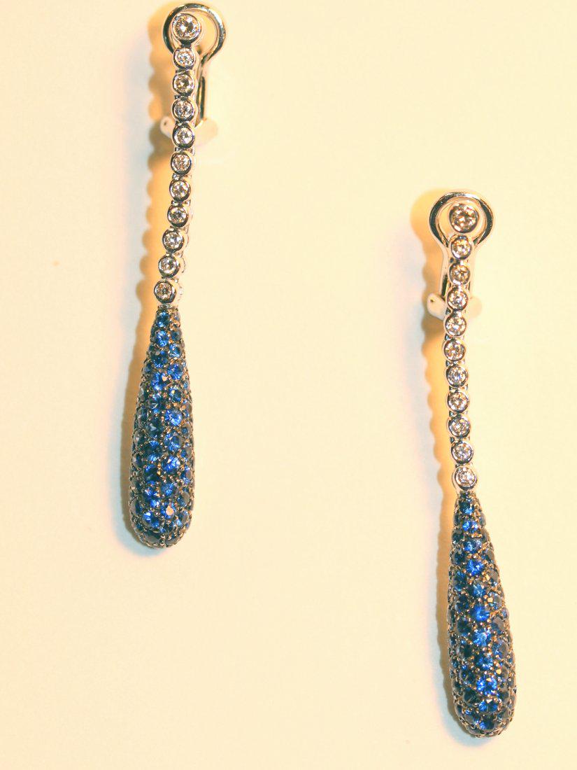 18K White Gold Drop Sapphire & Diamond Earrings: 18k white gold earrings with omega clip backs with posts. Each earring consists of eleven bezel set, round brilliant cut diamonds. Following is a teardrop with seventy-one pave set blue sapphires with