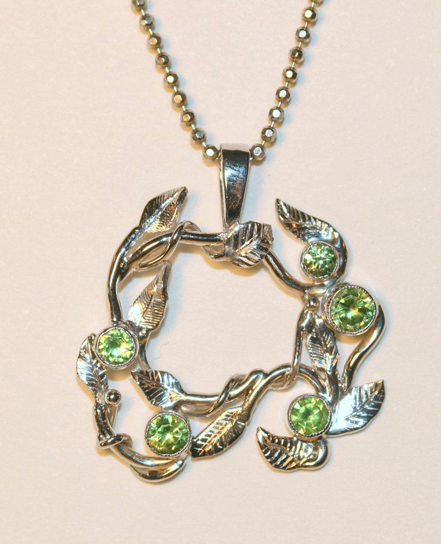14K White Gold Vine & Leaf Motif Circular Peridot: Vine and leaf motif cast 14k white gold pendant has five bezel set peridot set among the leaves. Included is a bead chain. Length: 18.5 inches TW of Colored Stones: 0.85ct TW of Unit: 7.38gm TW and si