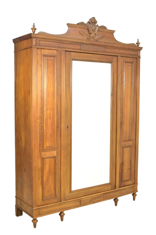 A LOUIS XVI STYLE OAK ARMOIRE: A LOUIS XVI STYLE OAK ARMOIRE Early 20th Century The rectilinear cornice is highlighted by a carved foliate motif which surmounts a recessed, conforming oak body housing three cabinets with three lock