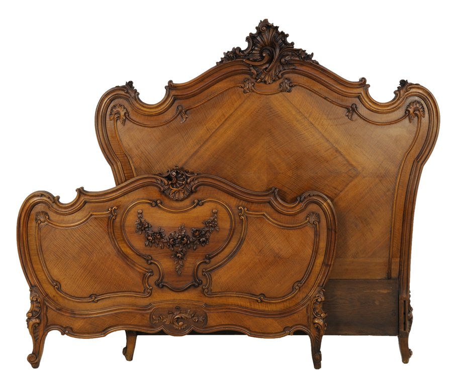 A LOUIS XV STYLE BED: A LOUIS XV STYLE BED Late 20th Century The shaped crest fail is highlighted by an intricately carved, ebonized scroll form motif surmounting carved reserves with floral and foliate details; raised on 