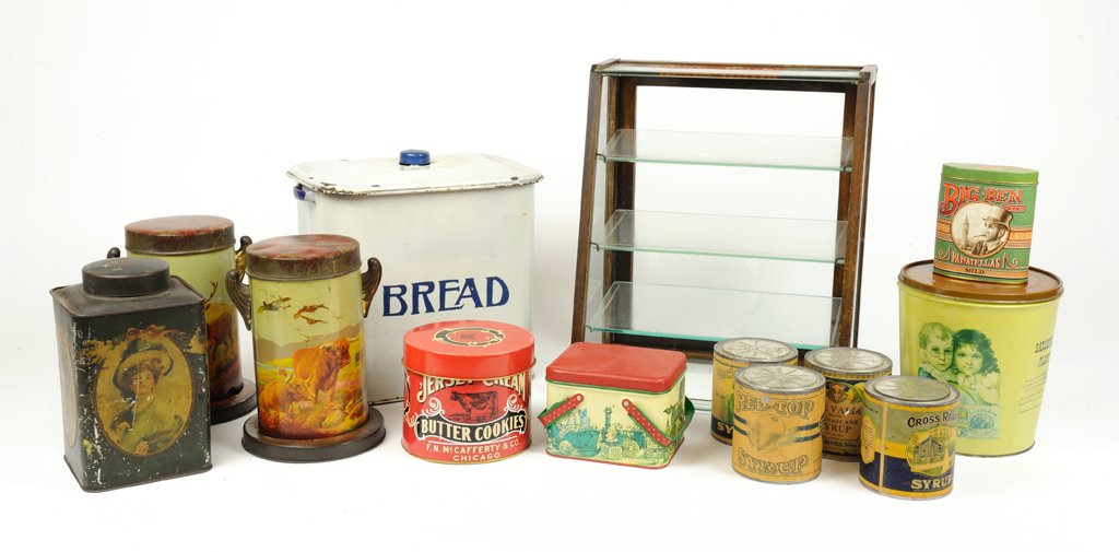 A LOT OF 12 VINTAGE TINS CANS AND A CANDY BAR CABINET: A LOT OF 12 VINTAGE TINS CANS AND A CANDY BAR CABINET 20th Century The collections of tins vary in style and size featuring a bread tin, branded tins, pastoral scenes, and women in period dress. Inclu