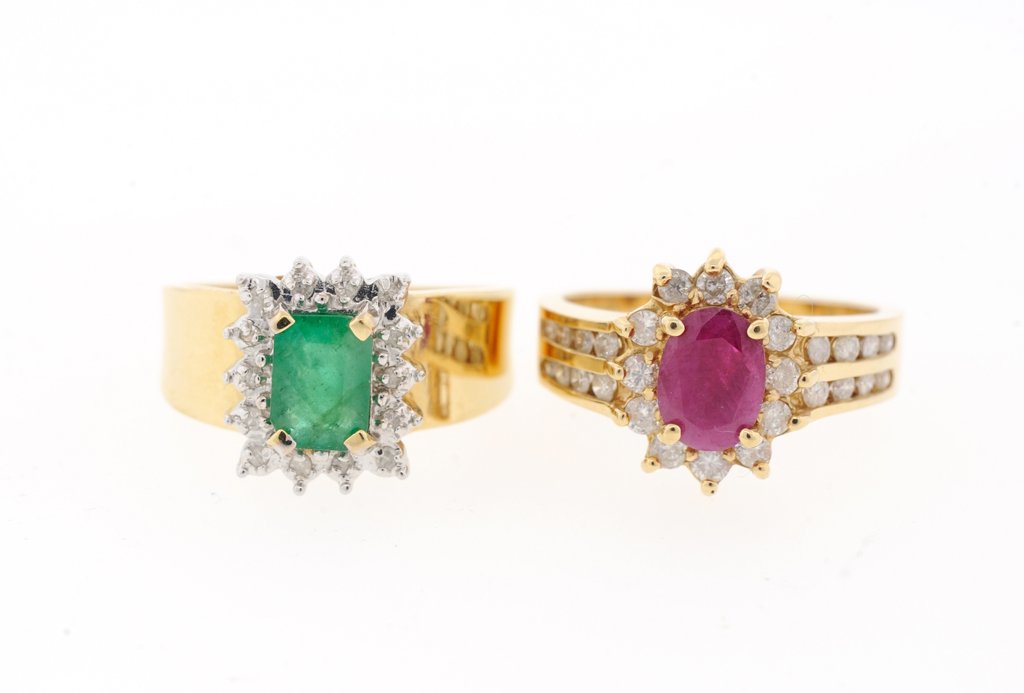 A PAIR OF RUBY AND EMERALD RINGS: A PAIR OF RUBY AND EMERALD RINGS A pair of ladies 14kt yellow gold rings featuring an emerald and a ruby in the center flanked by halo of diamonds. The rings have total of forty two single and round c