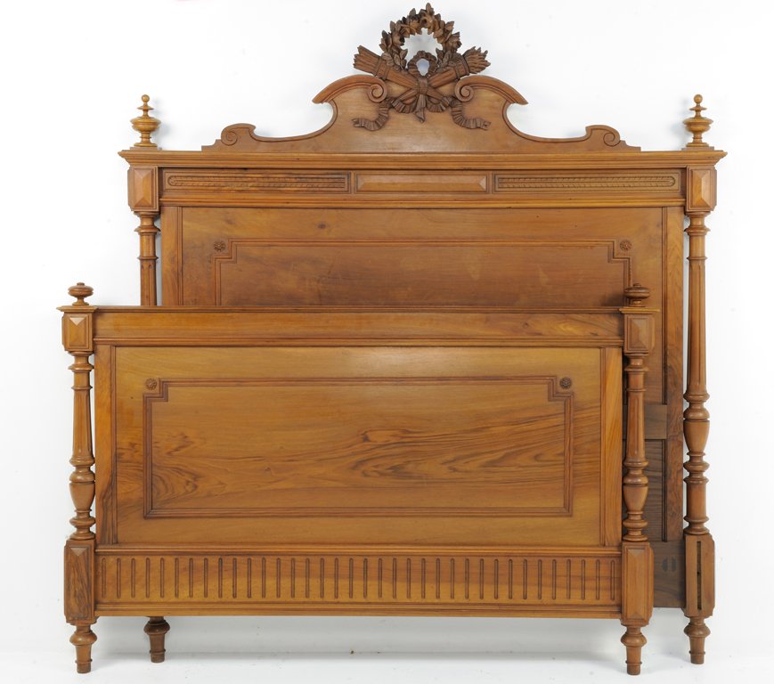 A NEOCLASSICAL STYLE WALNUT FINISH BED WITH WREATH AND : A NEOCLASSICAL STYLE WALNUT FINISH BED WITH WREATH AND TORCHIER Early 20th Century, France A Neoclassical style walnut finish bed with a pierced carved wreath and torchier crown flanked by two turned 