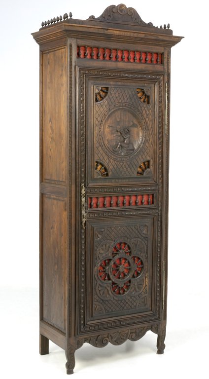 A FRENCH BRITTANY STYLE ARMOIRE WITH CARVED MUSICIAN: A FRENCH BRITTANY STYLE ARMOIRE WITH CARVED MUSICIAN Early 20th Century The carved, arched cornice flanked by finial details surmounts an intricately carved locking single door armoire highlighted by 