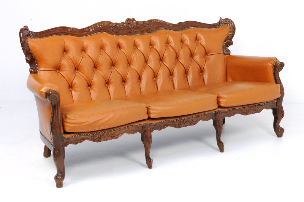 A VINTAGE LOUIS XV STYLE TUFTED ITALIAN LEATHER SETTEE: A VINTAGE LOUIS XV STYLE TUFTED ITALIAN LEATHER SETTEE Mid 20th Century A Louis XV style leather tufted settee with carved scrolling foliate, seats three, with rolled and covered armrests; raised on c