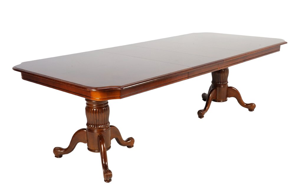 A CHIPPENDALE STYLE DINING ROOM DOUBLE PEDESTAL TABLE: A CHIPPENDALE STYLE DINING ROOM DOUBLE PEDESTAL TABLE FOR EIGHT 20th Century A Chippendale style dining room table with a shaped canted corner is raised on reed carved triffid double pedestal uprights