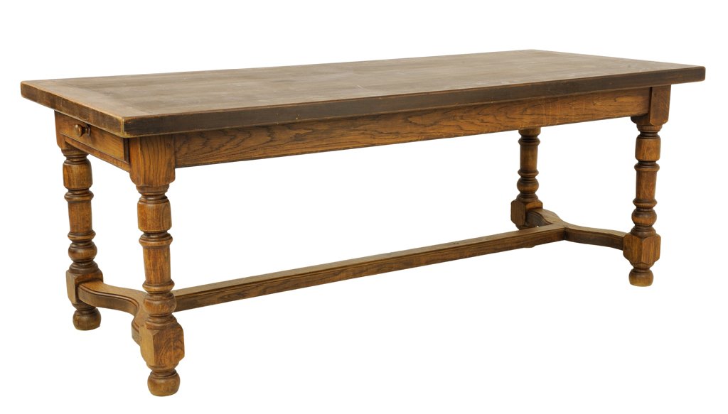 A RUSTIC FARM OAK TABLE: A RUSTIC FARM OAK TABLE Early 20th Century The oak plank top is supported by a recessed, conforming body housing two drawers at the head and foot of the table; supported by turned legs joined by a mod