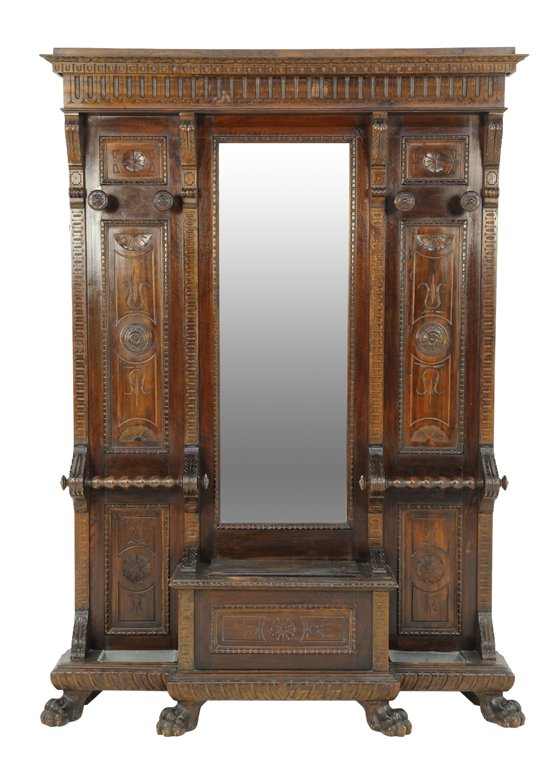 A RENAISSANCE REVIVAL STYLE CARVED WALNUT HALL TREE: A RENAISSANCE REVIVAL STYLE CARVED WALNUT HALL TREE Early 20th Century A reeded frieze above a walnut body featuring hooks and a centered mirror surmounting a stepped seat with storage flanked by umbr