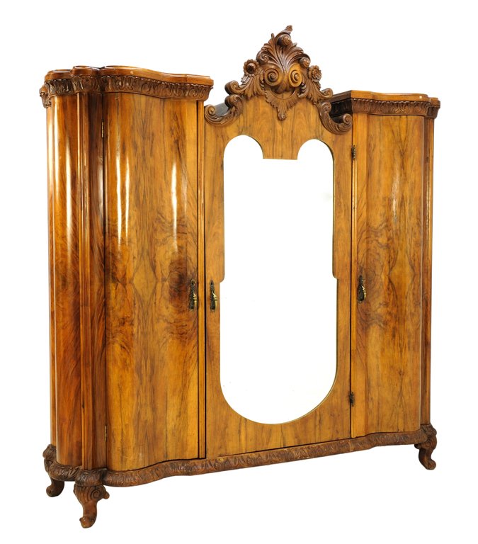 A VENETIAN BAROQUE STYLE TRIPLE DOOR SERPENTINE ARMOIRE: A VENETIAN BAROQUE STYLE TRIPLE DOOR SERPENTINE ARMOIRE WITH A FLAMED WALNUT FINISH 20th Century A Venetian Baroque style triple door armoire features an arched cornice with heavily carved scrolling f
