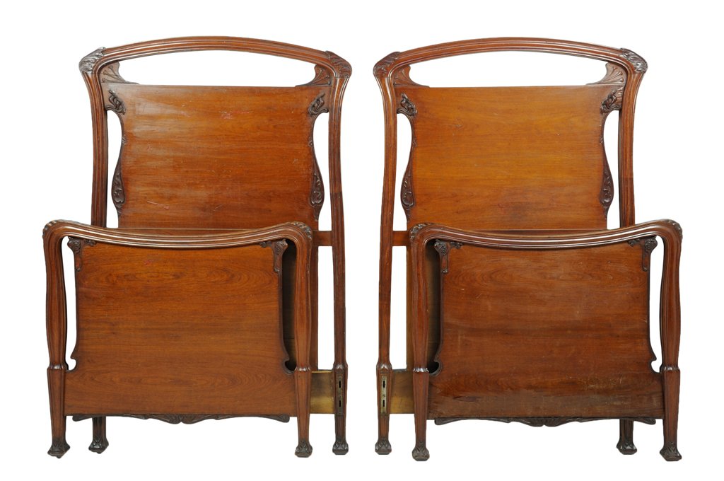 A PAIR OF ITALIAN ARTE NUOVA WALNUT BEDS: A PAIR OF ITALIAN ARTE NUOVA WALNUT BEDS Early 20th Century, Italy The pair of walnut carved beds features curved pierced crest with carved foliate and bud forms, rest on carved Gothic style foliate f