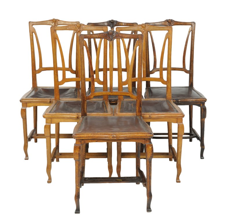A SET OF SIX ITALIAN ART NOUVEAU STYLE OAK CHAIRS: A SET OF SIX ITALIAN ART NOUVEAU STYLE OAK CHAIRS Early 20th Century Each chair features a carved floral motif at the crest rail above an open splat back above a leather seat raised on slender, taperi