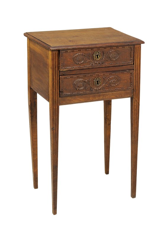 A FRENCH PROVINCIAL STYLE OAK TABLE: A FRENCH PROVINCIAL STYLE OAK TABLE The two drawer table with carved foliate decoration centered by gilt metal ribbon-tied escutcheon, raised on tapering legs. 27½ x 17¼ x 12 inches.