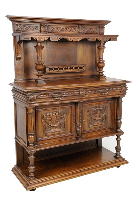A RENAISSANCE REVIVAL WALNUT SERVER: A RENAISSANCE REVIVAL WALNUT SERVER The stepped cornice raised on baluster form supports, above the rectangular surface over two short drawers and two paneled doors with basket and fruit decoration, r
