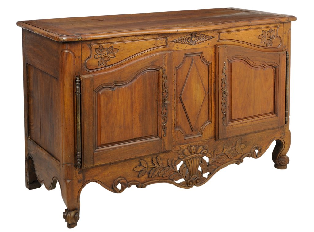 A FRENCH PROVINCIAL STYLE WALNUT BUFFET: A FRENCH PROVINCIAL STYLE WALNUT BUFFET The rectangular sideboard with leaf and rosette carved frieze over two paneled doors, centered with a carved diamond, above a shaped apron with basket and leafy