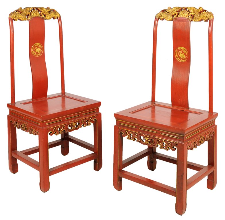A PAIR OF CHINESE CINNABAR STYLE RED LACQUER SIDE: A PAIR OF CHINESE CINNABAR STYLE RED LACQUER SIDE CHAIRS Each chair having a gilt painted crest depicting two dragons centered with a sun over the vertical back splat with a gilt painted medallion dep