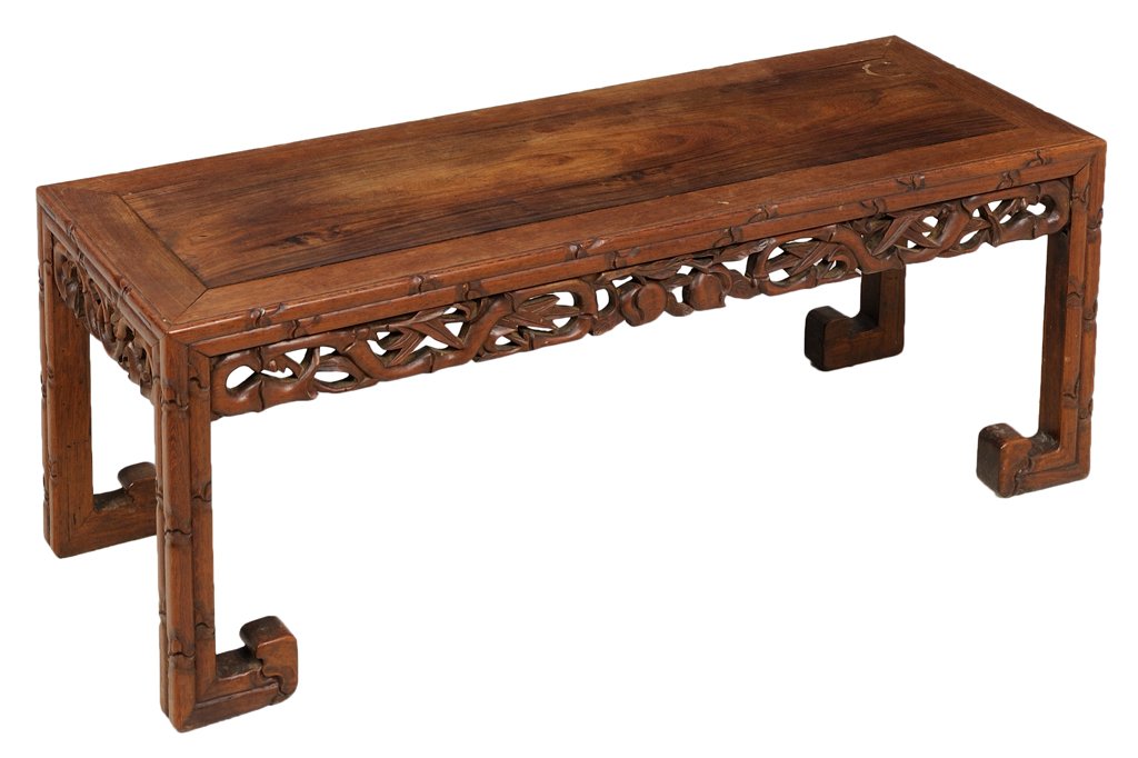 A CHINESE CARVED LOW TABLE: A CHINESE CARVED LOW TABLE The low table having a rectangular top within faux bamboo border, a pierce carved frieze with scrolling leaf and fruit decoration, raised on bamboo form legs, ending in squa