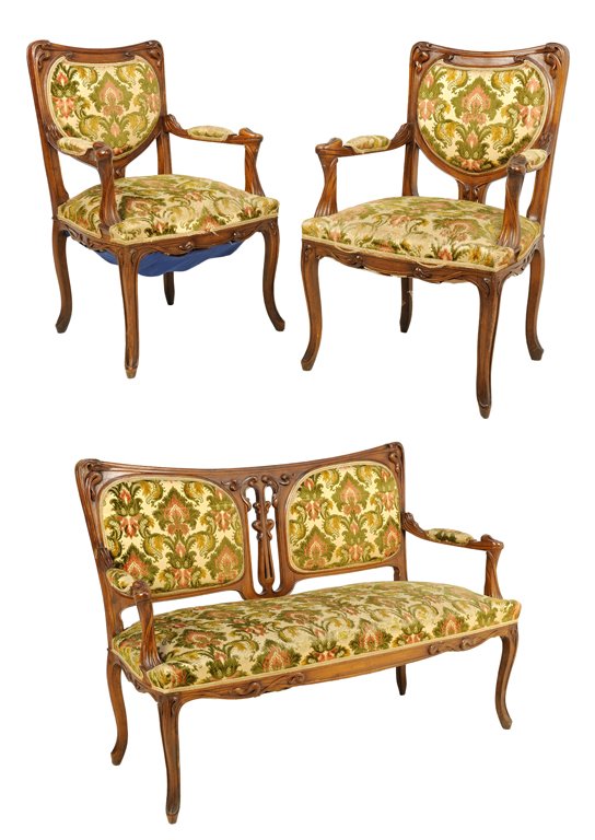 AN ART NOUVEAU STYLE UPHOLSTERED PARLOR SUITE: AN ART NOUVEAU STYLE UPHOLSTERED PARLOR SUITE The suite comprising a settee and two armchairs. Each having a curved crest rail with carved stylized foliate decoration over the upholstered back and sea