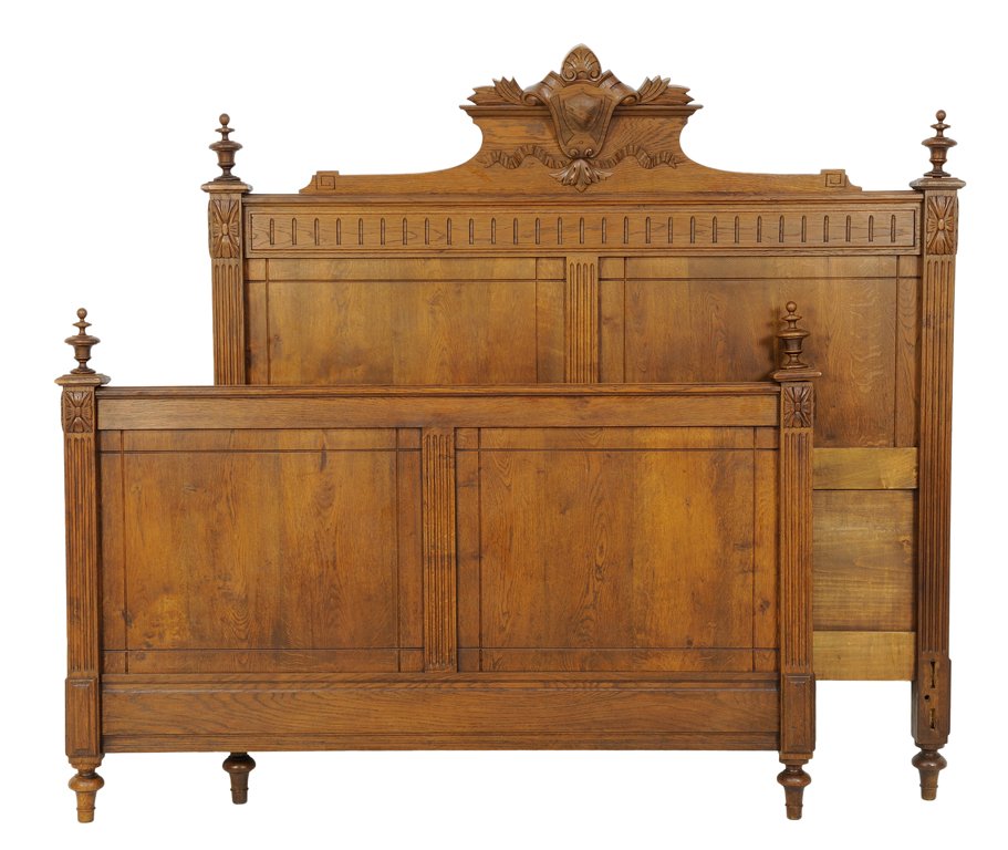 A FRENCH LOUIS XVI STYLE OAK BED: A FRENCH LOUIS XVI STYLE OAK BED The bed top rail having a shield and shell carved crest to headboard, flanked by turned finials, raised on toupie feet. Comprising headboard, footboard and side rails.